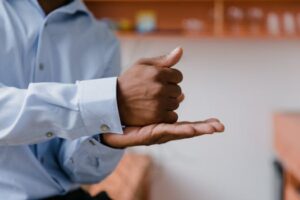 A man using sign language indoors with a focus on hand gestures and communication.